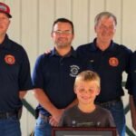 An 8-year-old Indiana boy spotted a smoking camper trailer and alerted people nearby before it caught fire; he was honoured with Department Patch and Certificate of Recognition for preventing a larger emergency